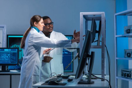 Foto de Diversos equipos de ingenieros microelectrónicos discuten los desarrollos actuales en un moderno laboratorio de ciencias. Lugar de trabajo de diseñadores de microprocesadores. El concepto de innovaciones e invenciones del futuro. - Imagen libre de derechos