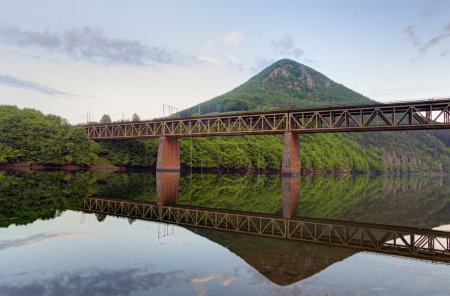 Lago con puente de montaña y ferrocarril
