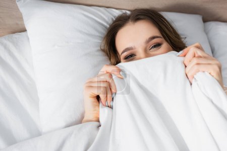 Téléchargez les photos : Vue du dessus de la jeune femme couvrant le visage avec couverture - en image libre de droit