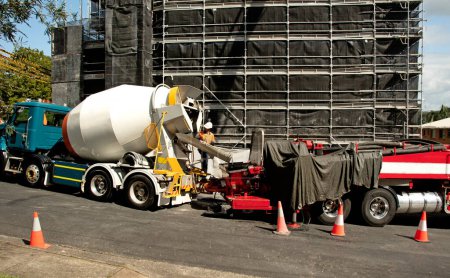 Photo for Concrete Truck delivering material to a Boom Pump at the building site. New social housing residential home units development at 56-58 Beane St. Gosford. March 30, 2021. Part of a series landscape image. Australia. - Royalty Free Image