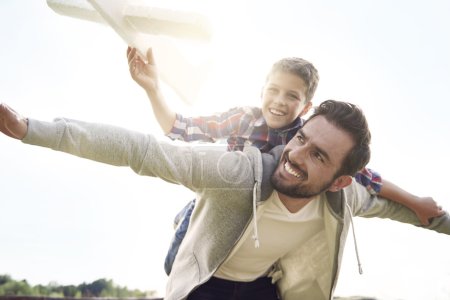 Photo for Father and son testing a paper plane - Royalty Free Image