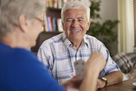 Abuelos alegres jugando a las cartas
