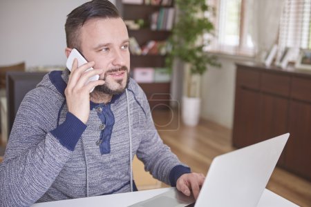 El hombre trabaja en el ordenador portátil y teléfono móvil
