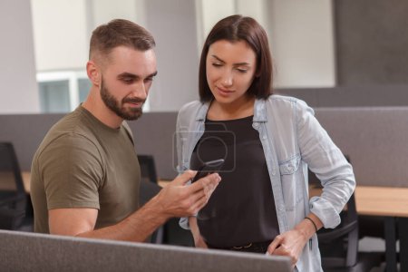 Foto de Atractiva mujer de negocios y su colega masculino viendo algo en un teléfono inteligente - Imagen libre de derechos