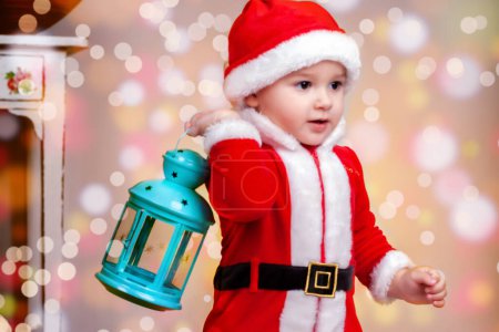 A little boy in a Santa costume holds a blue flashlight