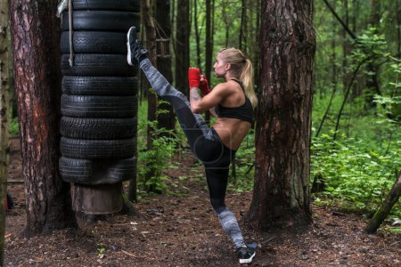 Photo for Woman practising kickboxing performing a leg axe kick working out outdoors. - Royalty Free Image