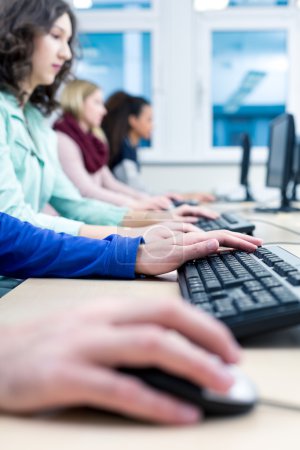 Foto de Tiro de jóvenes estudiantes sentados en fila en una sala de computadoras - Imagen libre de derechos