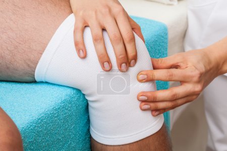 Photo for Physiotherapist doing patellar mobilisation after knee injury - Royalty Free Image