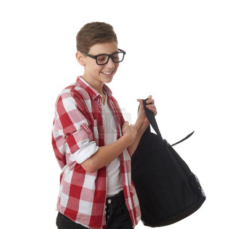 Téléchargez les photos : Adolescent mignon garçon en chemise à carreaux rouges et lunettes mettant sac d'école sur fond blanc isolé, demi-corps, comme école, concept d'éducation - en image libre de droit