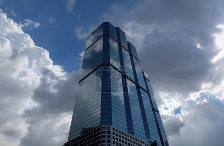 Photo for Bangkok, Thailand - July 10, 2019 :  Angular geometric mirror cladding on a modern building with repeating structure and reflected sky and clouds. No focus, specifically. - Royalty Free Image