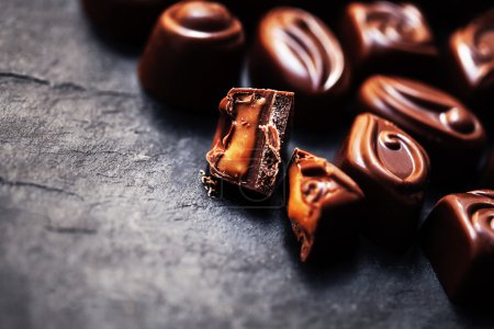 Foto de Chocolate sobre fondo negro. Dulces de chocolate, cacao. Surtido de chocolates finos de cerca - Imagen libre de derechos