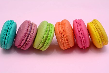 Multicolored macarons on a pink background, close-up.