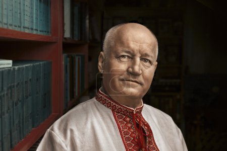 Photo for Portrait of a man in the Ukrainian national shirt -  background of bookshelves (writer Oles Volaya) - Royalty Free Image