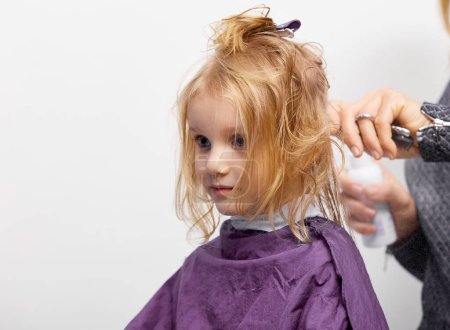 Photo for Hair cutting process. Beautiful little girl at the barber shop, hairdresser making a hair style to cute caucasian 4-5 year old little girl - Royalty Free Image