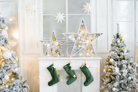 Decoración de Navidad de la chimenea blanca en la sala de estar. Estrellas de hadas y calcetines para Santa Claus