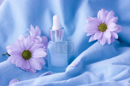 Foto de Delicate purple background with a bottle of face cream, hands, with pink flowers, the concept of eternal youth. - Imagen libre de derechos