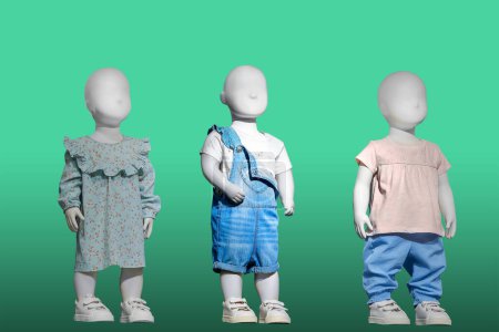 Tres maniquíes vestidos con ropa de moda para niños, aislados sobre fondo verde. No hay marcas u objetos de copyright. Tres maniquíes vestidos con ropa de moda para niños, aislados sobre fondo verde. No hay marcas u objetos de copyright.