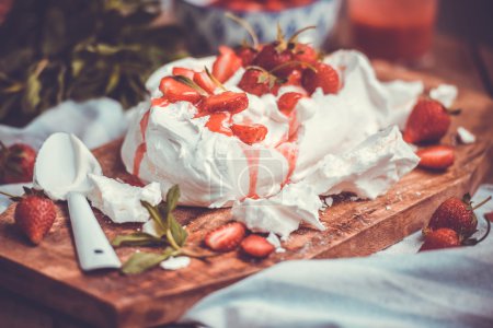 Foto de Un clásico postre de verano británico llamado Eton Mess. Fresas, merengue machacado y crema batida sobre tabla de madera. Imagen tonificada - Imagen libre de derechos