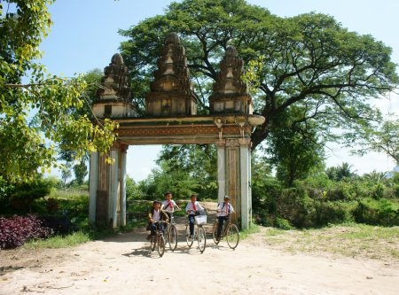 Grupo de niños asiáticos, bicicleta de montar, Khmer puerta de la aldea
