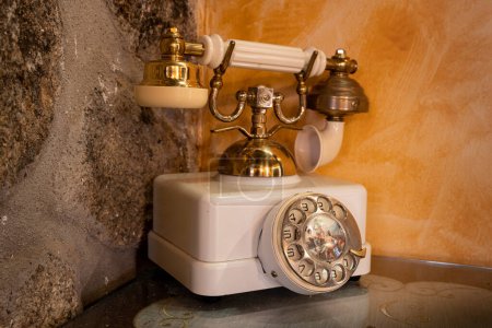 Un viejo teléfono retro blanco con marcación giratoria en una mesa
