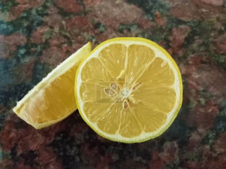 Un primer plano de rebanada jugosa fresca y medio limón sobre un fondo de granito oscuro Un primer plano de rebanada jugosa fresca y medio limón sobre un fondo de granito oscuro