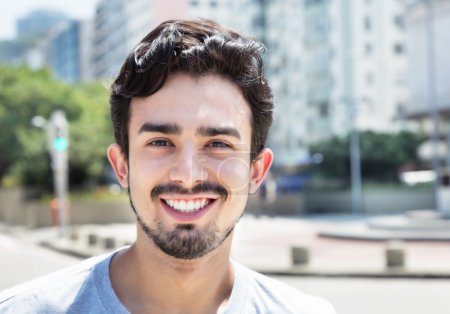 Handsome hispanic guy in a grey shirt in city