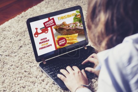 Mujer pidiendo comida para llevar por Internet con un ordenador portátil mientras se relaja en casa
.