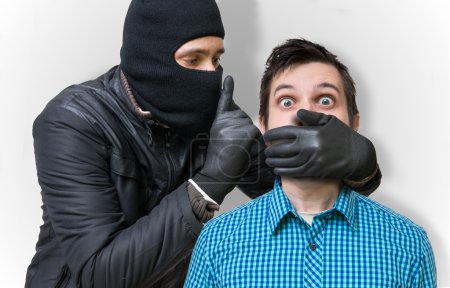 Photo for Aggressive masked terrorist or burglar with balaclava assault and takes man hostage. - Royalty Free Image