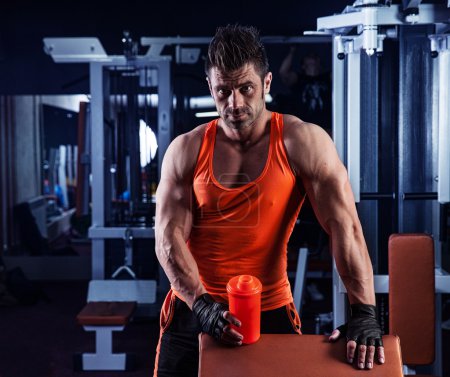 joven musculoso guapo bebe una proteína en el gimnasio
