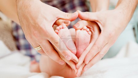 Foto de Los pies de los niños en manos de la madre y el padre. Los pies del niño pequeño recién nacido arriba de las manos de la forma caliente. Padres e hijos. Concepto de familia feliz. Hermosa imagen conceptual de la maternidad - Imagen libre de derechos