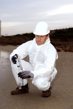 Trabajador en traje de protección que examina la contaminación
