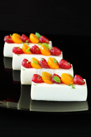 Photo for White Chocolate Mousse with Raspberries, Physalis and Mint Leaves, on a black background. - Royalty Free Image