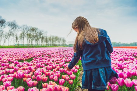 entzückendes kleines Mädchen spielt mit Blumen auf einer Tulpenfarm