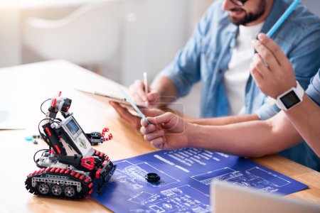 Téléchargez les photos : Coopérer les uns avec les autres. Confrères professionnels agréables assis à la table et travaillant sur le projet ensemble - en image libre de droit