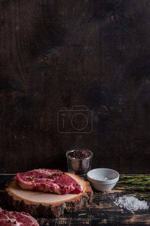 Raw juicy meat steak on dark wooden background ready to roasting