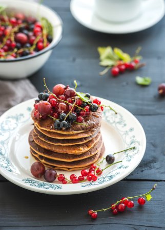 Photo for Breakfast set. Buckwheat pancakes with fresh berries and honey on rustic plate over black wooden table - Royalty Free Image