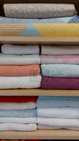 Photo for Multi-colored cotton terry towels stacked neatly on the shelves in the closet. Home textile background - Royalty Free Image