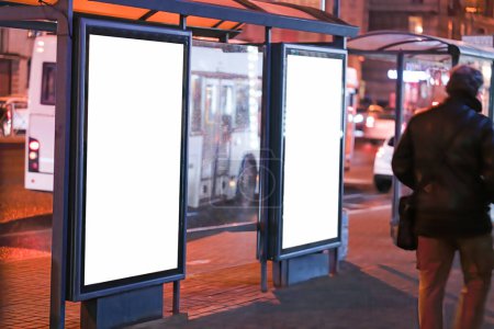 Publicidad cartel vertical en la ciudad brilla por la noche. MOCKUP para el diseño Publicidad cartel vertical en la ciudad brilla por la noche. MOCKUP para el diseño