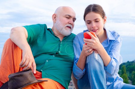 Foto de Nieta con abuelo mayor. Hombre mayor Abuelo con teléfono móvil sonriente hacer autorretrato webcam ver. Mayores generaciones más jóvenes - Imagen libre de derechos