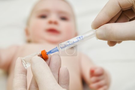 Photo for Doctor holds syringe to vaccinate  6 months baby with injection - Royalty Free Image