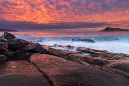 Colorido paisaje marino de salida del sol con alto cielo lleno de nubes desde North Pearl Beach en la costa central, NSW, Australia.