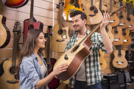 Photo for Man is showing girl guitar in a music store. - Royalty Free Image