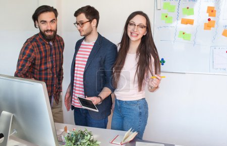 Téléchargez les photos : Une équipe de start-up de trois jeunes hipsters dans un bureau moderne collaborant - en image libre de droit