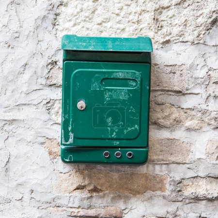 Old green mailbox attached to a stone wall.