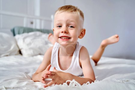 Photo for A beautiful little boy with blue eyes is lying on the bed. - Royalty Free Image