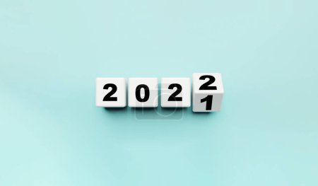 Bloque de cubo blanco volteando de 2021 a 2022 sobre fondo azul, preparación para feliz Navidad y feliz año nuevo y 3d concepto de renderizado.