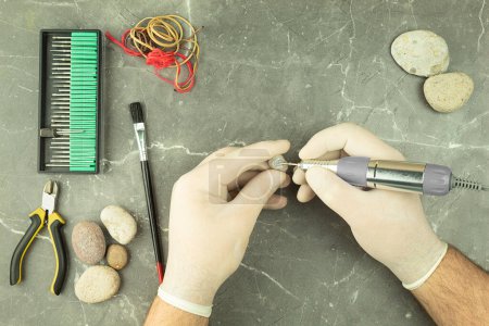 Photo for The hands of a man engrave the stone with the help of an engraver. Professional engraving on stones and metal. Background with place for text - Royalty Free Image
