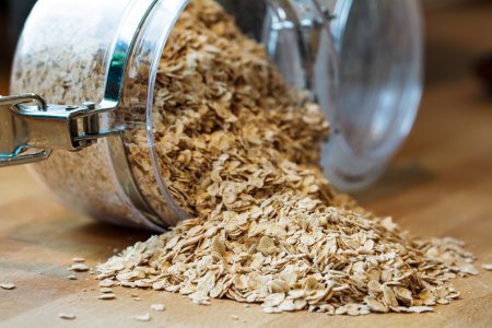 Foto de Avena de avena enrollada cayendo de un frasco de vidrio - Imagen libre de derechos