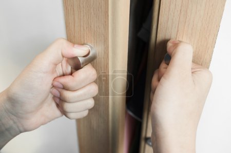 Foto de Primer plano Las manos de la mujer se sostiene en las manijas de la puerta del gabinete, manijas de la puerta del armario o del armario - Imagen libre de derechos