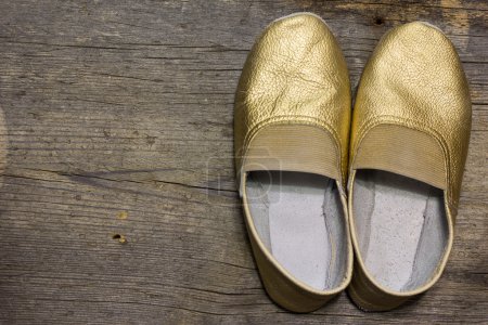 Photo for Gilded gymnastic slippers from skin on a floor - Royalty Free Image